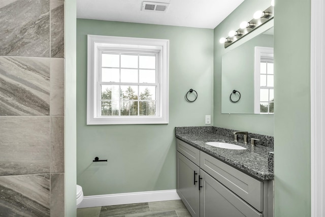 bathroom with toilet, vanity, and plenty of natural light