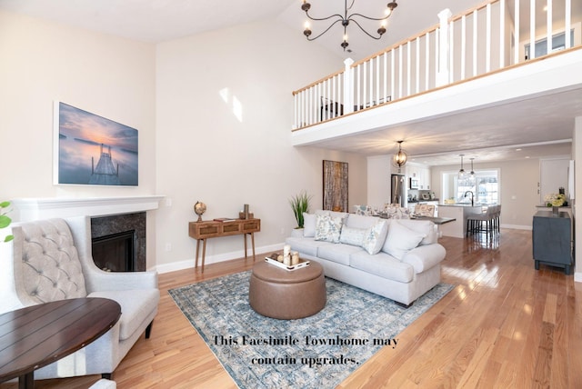 living room featuring sink, a high ceiling, a chandelier, and hardwood / wood-style flooring