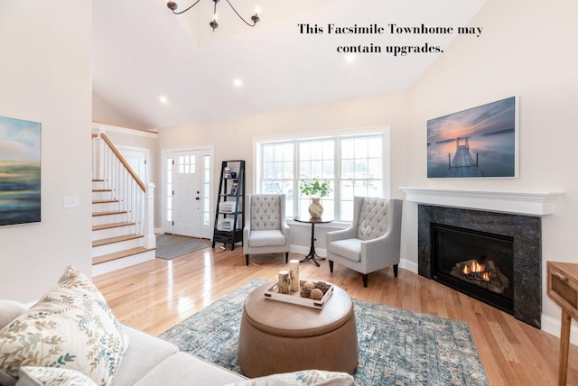 living room with high vaulted ceiling, light wood-type flooring, and an inviting chandelier