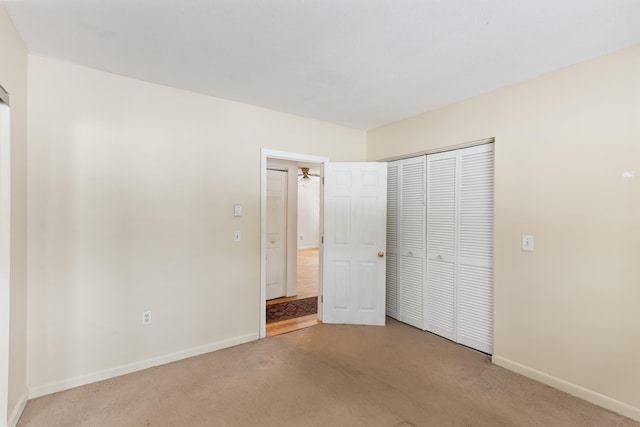 unfurnished bedroom featuring a closet and light colored carpet