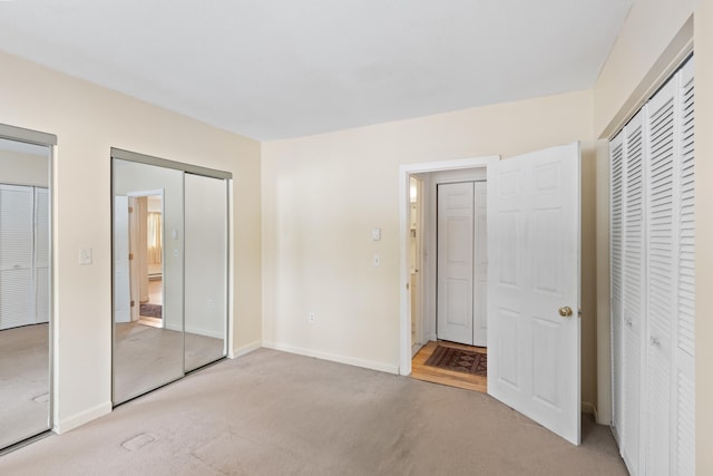 unfurnished bedroom featuring two closets and light colored carpet