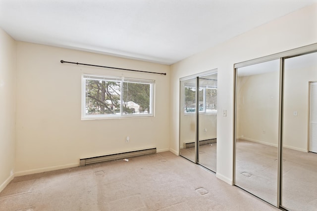 unfurnished bedroom featuring baseboard heating, light carpet, and multiple closets