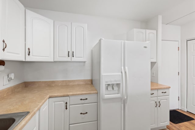 kitchen featuring white cabinets, white refrigerator with ice dispenser, and light hardwood / wood-style flooring