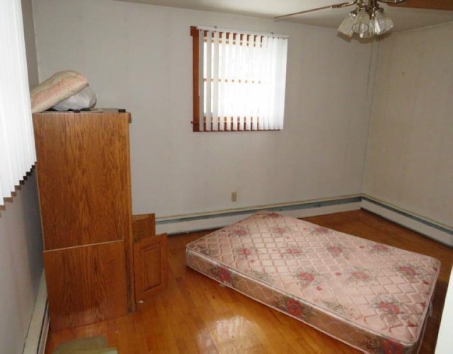 bedroom with ceiling fan, hardwood / wood-style floors, and a baseboard radiator