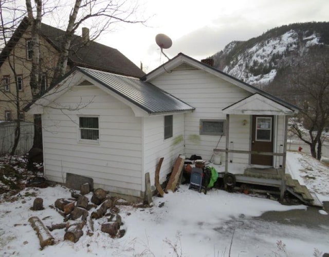 snow covered back of property featuring a mountain view