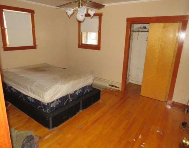 bedroom featuring a closet, ceiling fan, hardwood / wood-style flooring, and crown molding