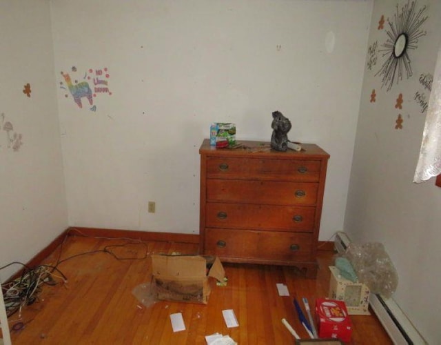 bedroom with a baseboard radiator and dark hardwood / wood-style floors