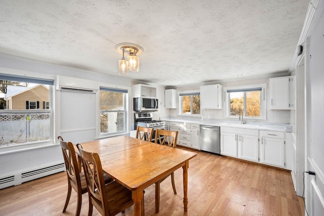 dining area with sink, a textured ceiling, an AC wall unit, light wood-type flooring, and baseboard heating