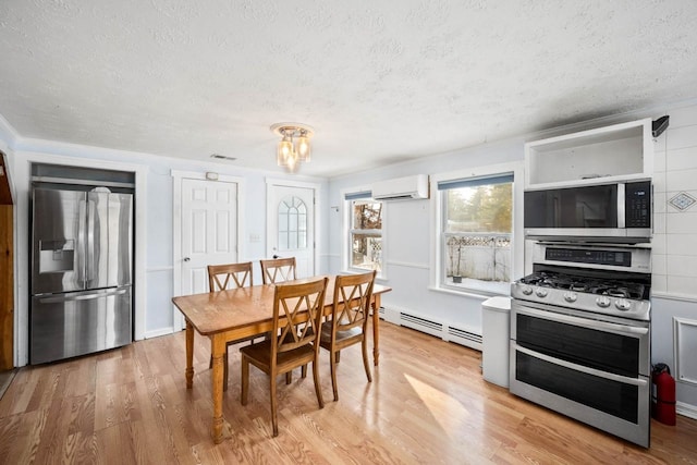 dining area featuring baseboard heating, a wall mounted AC, light hardwood / wood-style floors, and a textured ceiling