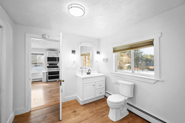 bathroom with toilet, a baseboard radiator, vanity, and hardwood / wood-style floors