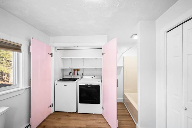 laundry area featuring light hardwood / wood-style floors, a textured ceiling, and independent washer and dryer