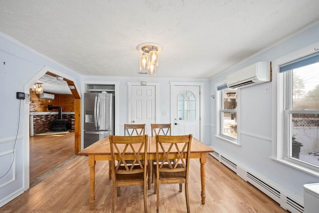 dining area featuring light hardwood / wood-style floors, a baseboard heating unit, a wood stove, and a wall mounted AC