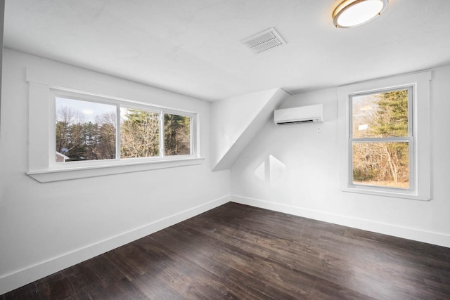 additional living space with an AC wall unit and dark hardwood / wood-style floors