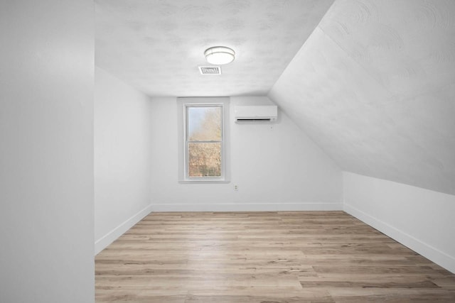 bonus room featuring a wall unit AC, vaulted ceiling, and light hardwood / wood-style flooring