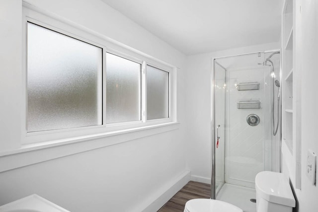 bathroom featuring toilet, an enclosed shower, and wood-type flooring