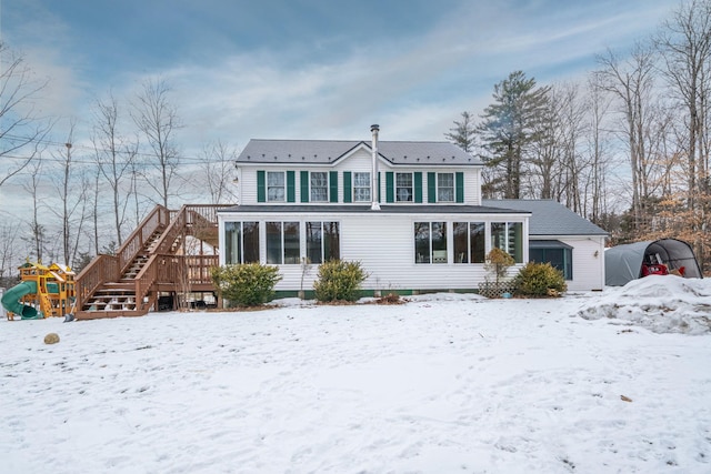 snow covered house featuring a sunroom