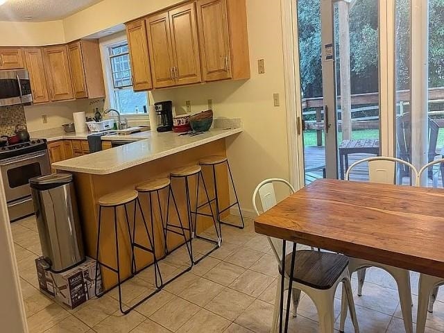 kitchen featuring appliances with stainless steel finishes, decorative backsplash, and kitchen peninsula