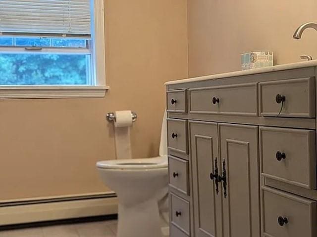 bathroom featuring tile patterned flooring, toilet, and a baseboard heating unit