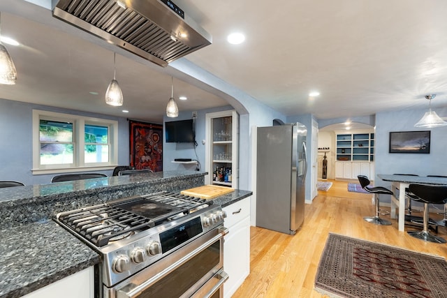 kitchen with wall chimney exhaust hood, white cabinetry, hanging light fixtures, and appliances with stainless steel finishes