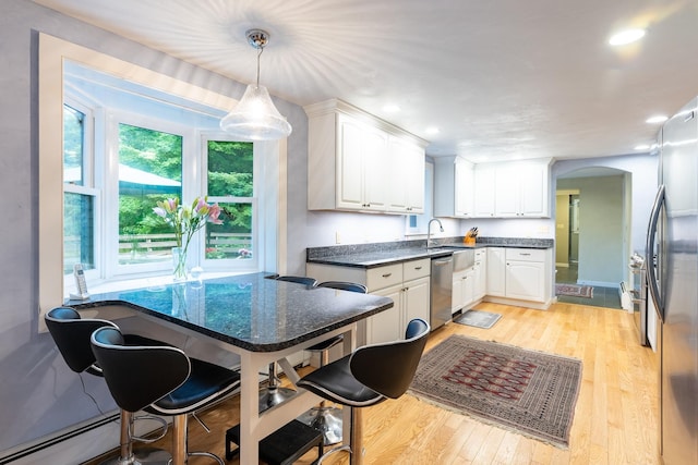 kitchen featuring stainless steel appliances, decorative light fixtures, white cabinetry, a kitchen bar, and light wood-type flooring