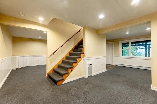 basement with a baseboard heating unit and dark colored carpet