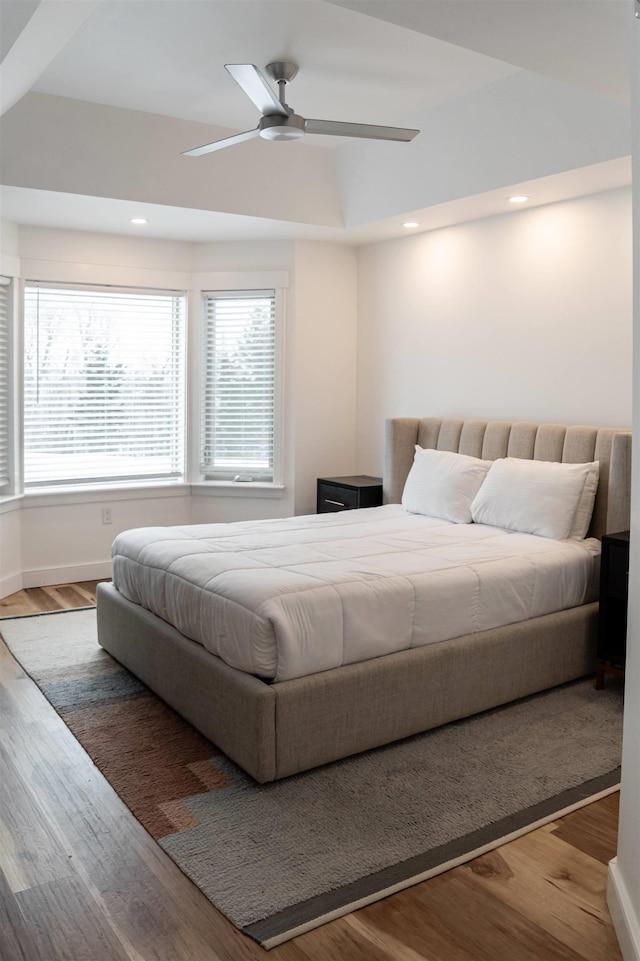 bedroom featuring hardwood / wood-style floors, ceiling fan, and a tray ceiling