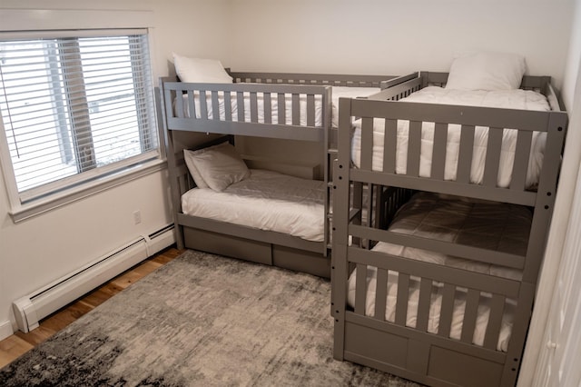 bedroom with wood-type flooring and a baseboard heating unit