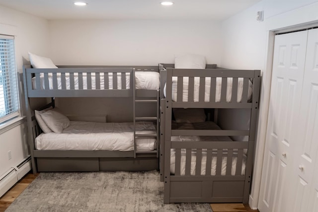 bedroom featuring wood-type flooring, a closet, and a baseboard heating unit