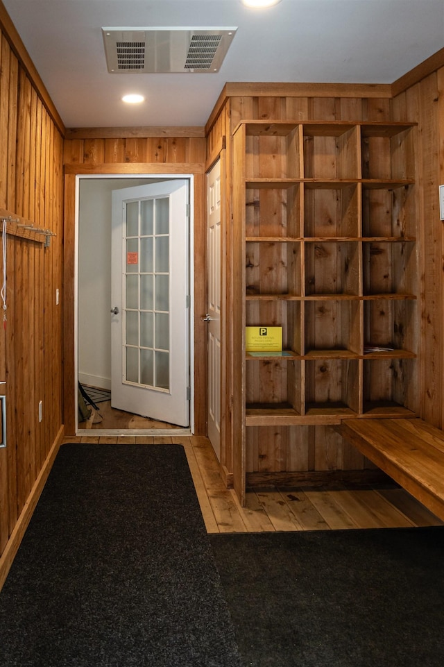 mudroom featuring light carpet and wood walls