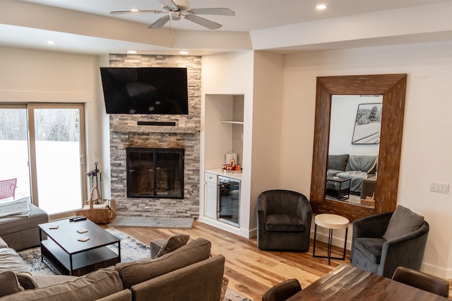 living room featuring ceiling fan, light hardwood / wood-style flooring, a fireplace, and wine cooler