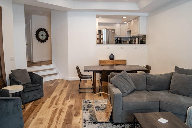 living room with light hardwood / wood-style floors and a raised ceiling