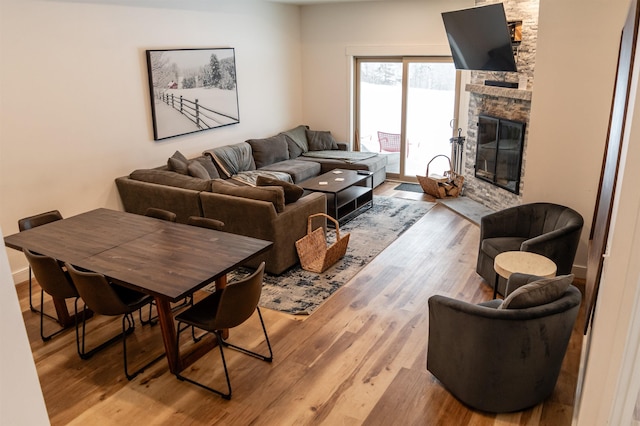 living room with hardwood / wood-style flooring and a stone fireplace