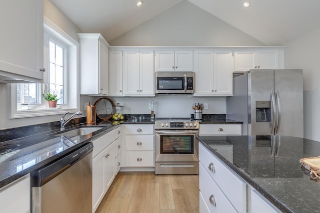 kitchen featuring white cabinets, stainless steel appliances, dark stone counters, and sink