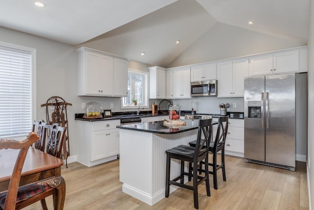 kitchen with stainless steel appliances, white cabinets, a center island, and light hardwood / wood-style flooring