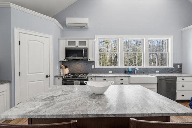 kitchen featuring stainless steel appliances, white cabinets, a center island, lofted ceiling, and a wall mounted AC