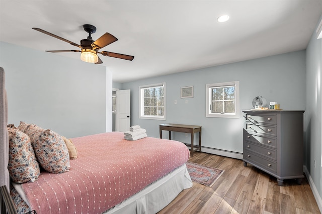 bedroom with ceiling fan, baseboard heating, and light hardwood / wood-style flooring