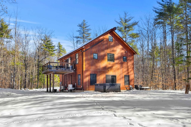 view of snowy exterior featuring a hot tub and a wooden deck