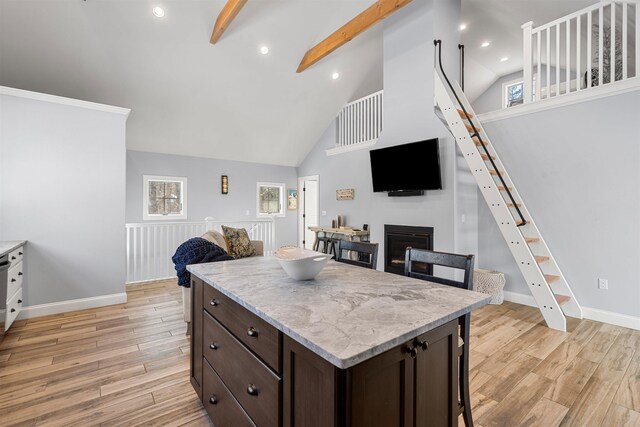 kitchen featuring a kitchen breakfast bar, light stone countertops, beamed ceiling, high vaulted ceiling, and dark brown cabinets