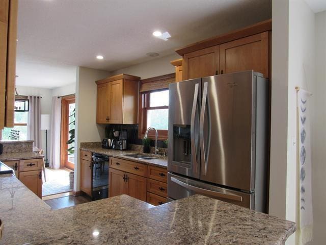 kitchen featuring plenty of natural light, stainless steel fridge, black dishwasher, and sink