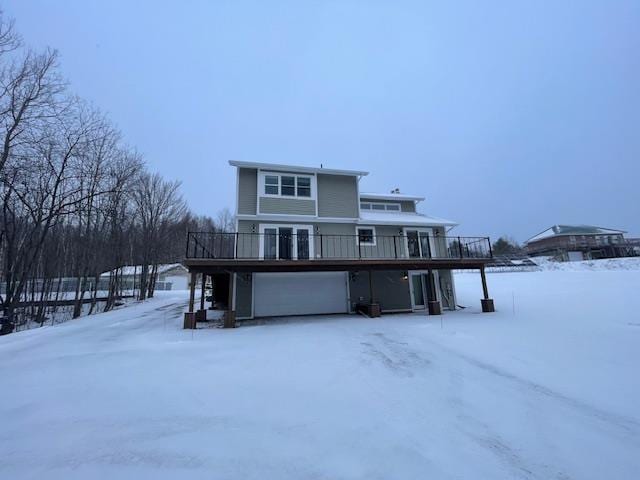 snow covered house with a deck and a garage