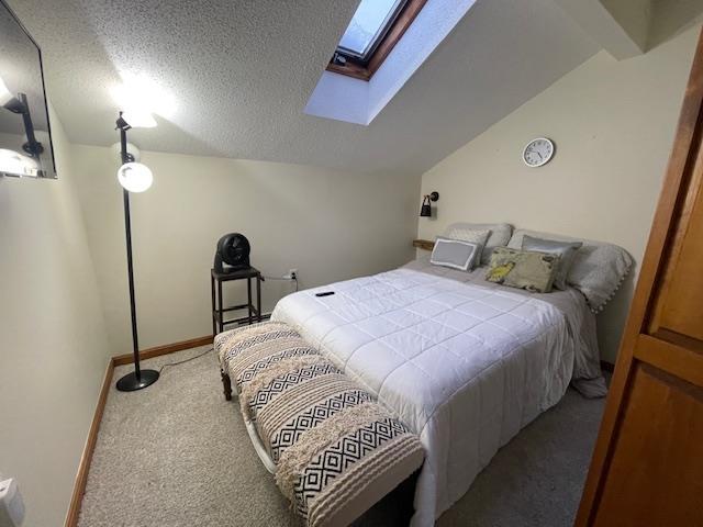 carpeted bedroom with a textured ceiling and vaulted ceiling with beams