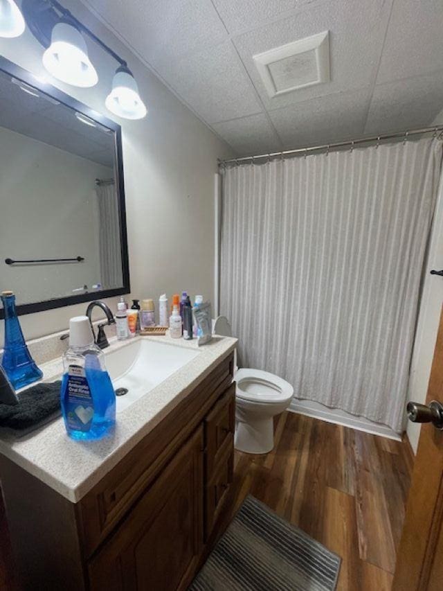 bathroom featuring toilet, vanity, a paneled ceiling, and hardwood / wood-style flooring