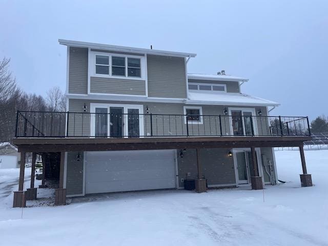 snow covered back of property with a garage