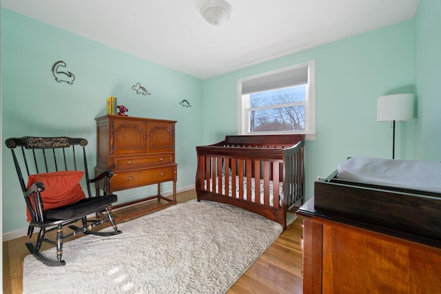 bedroom with light hardwood / wood-style flooring and a crib