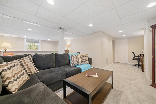 living room with a drop ceiling and light colored carpet