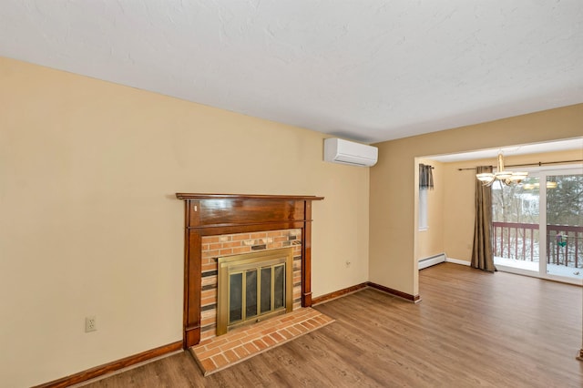 unfurnished living room featuring a fireplace, an inviting chandelier, an AC wall unit, wood-type flooring, and a baseboard radiator