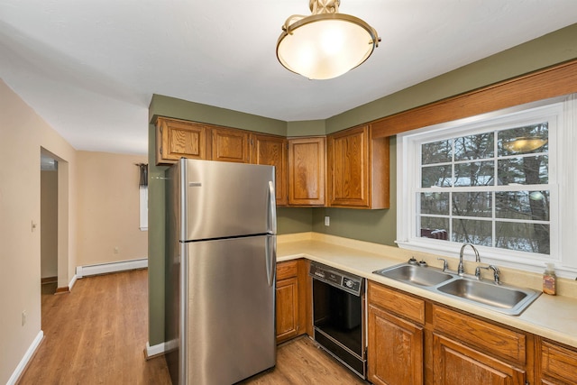 kitchen with light hardwood / wood-style floors, stainless steel fridge, a baseboard heating unit, sink, and black dishwasher