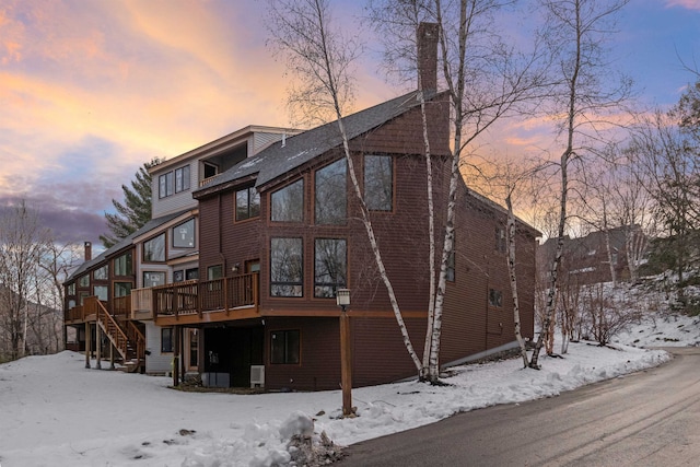 snow covered back of property with a wooden deck