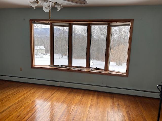 unfurnished room with a baseboard radiator, ceiling fan, and light hardwood / wood-style floors