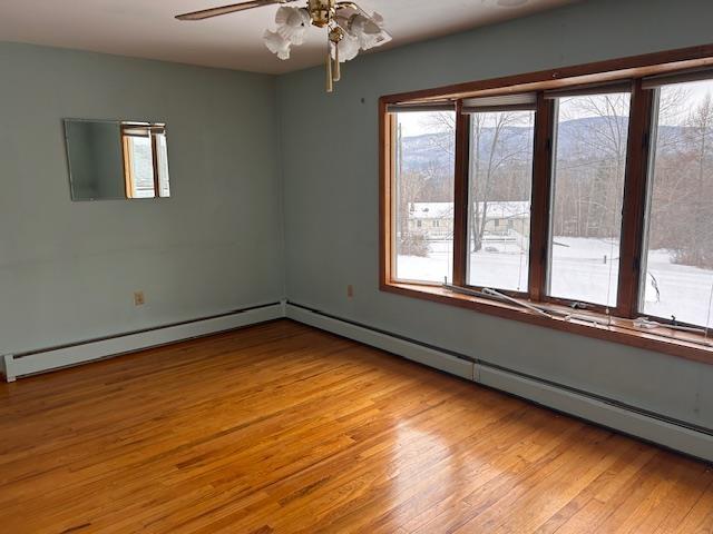 spare room with ceiling fan, light hardwood / wood-style floors, and a baseboard radiator